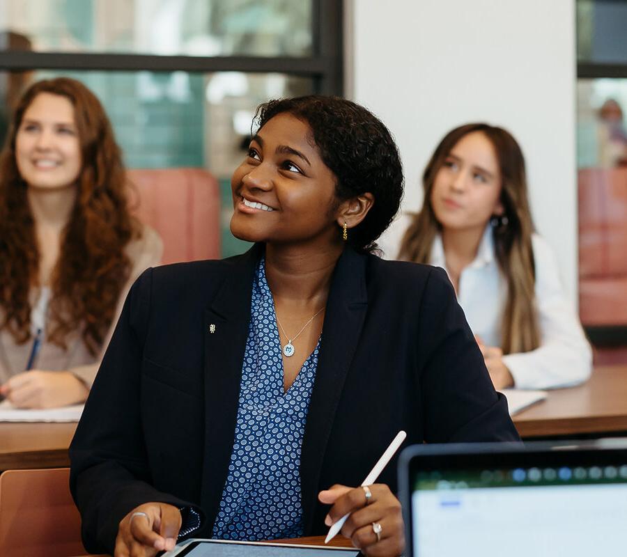 female students smiling 和 taking notes at 拼搏体育